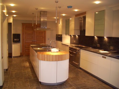 Wooden and white countertop kitchen with hanging lights. Modern design all completed by Airos, please contact us for more information or if you are interested in a similar design.